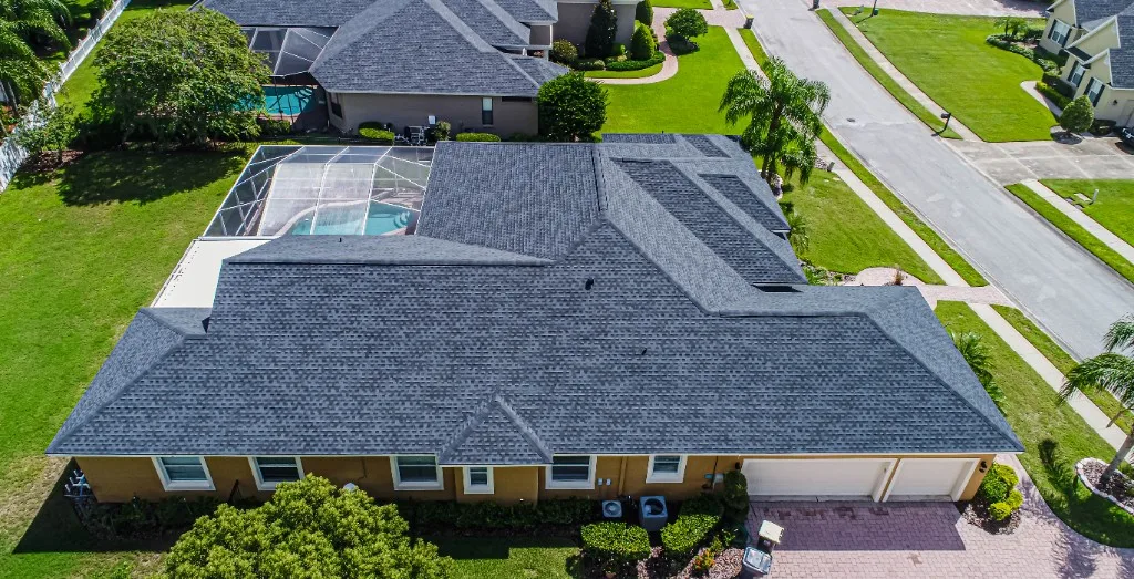 Aerial view of a completed Stronghold Roofing slate-blue architectural shingle roof on a Florida home with a screened pool cage