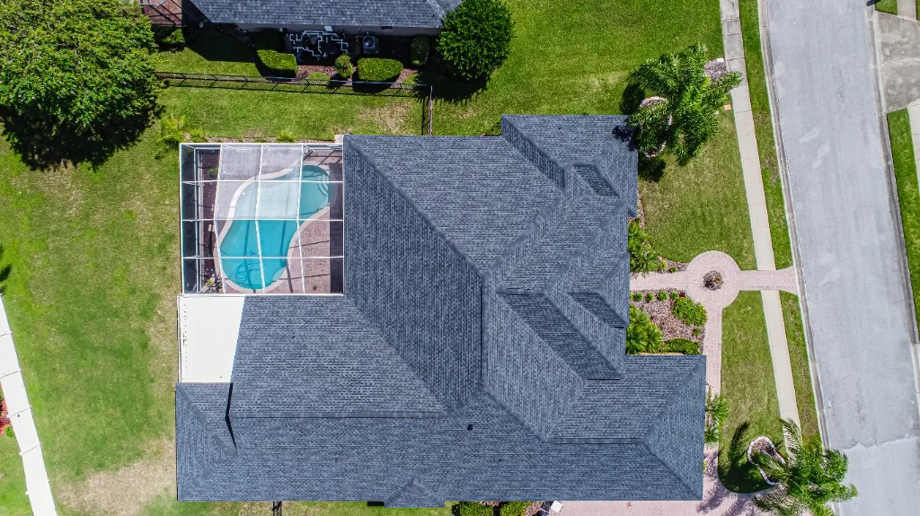 Top-down aerial view of a completed Stronghold Roofing charcoal architectural shingle roof on a Florida home with a screened pool cage