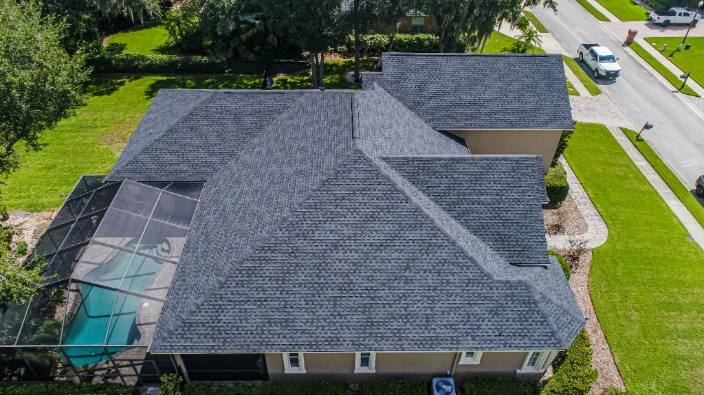 Aerial view of a completed Stronghold Roofing gray architectural shingle roof on a Florida home with a screened pool cage