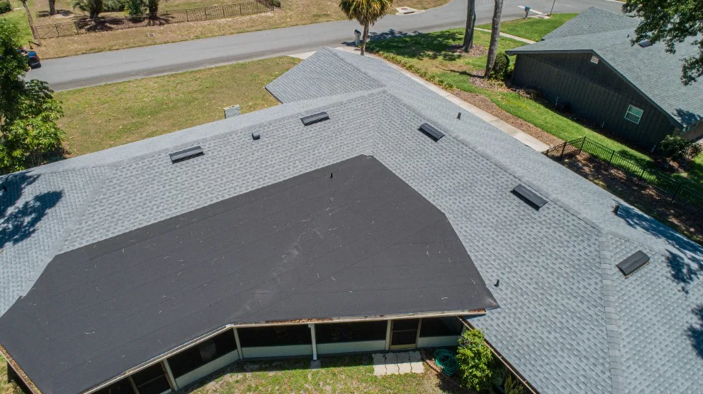 Aerial view of a Stronghold Roofing shingle re-roof mid-installation, with a low-slope section still on underlayment