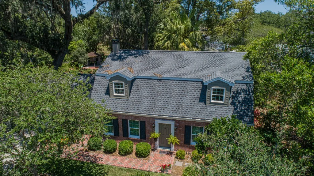 Aerial view of a completed Stronghold Roofing blue-gray architectural shingle roof on a Florida colonial-style home with two front-facing dormers