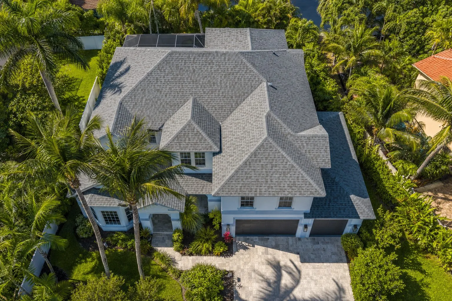 Gray shingle re-roof on a two-story home framed by palms