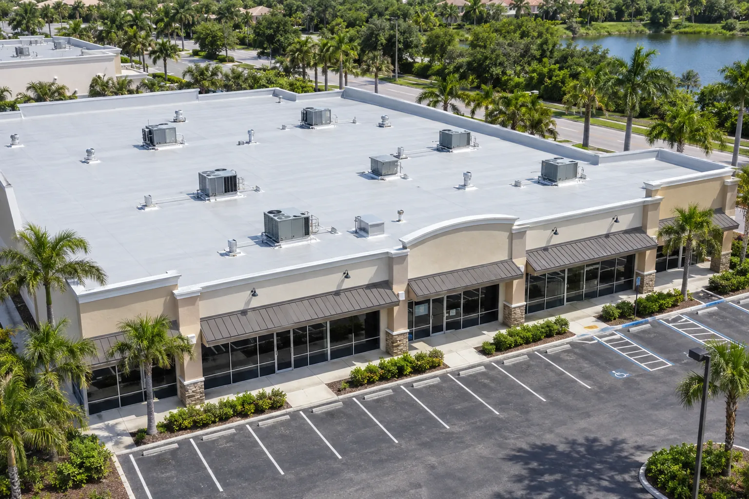 Aerial view of a Florida strip mall shopping center with a light gray PVC flat roof