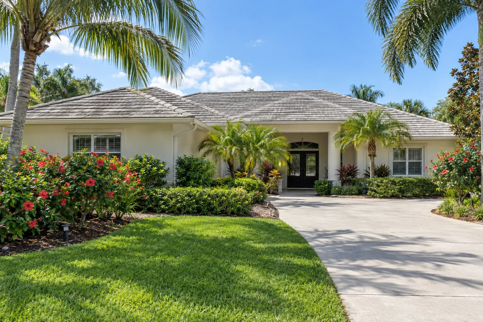 Florida ranch-style home with a weathered gray flat concrete tile roof and hibiscus landscaping