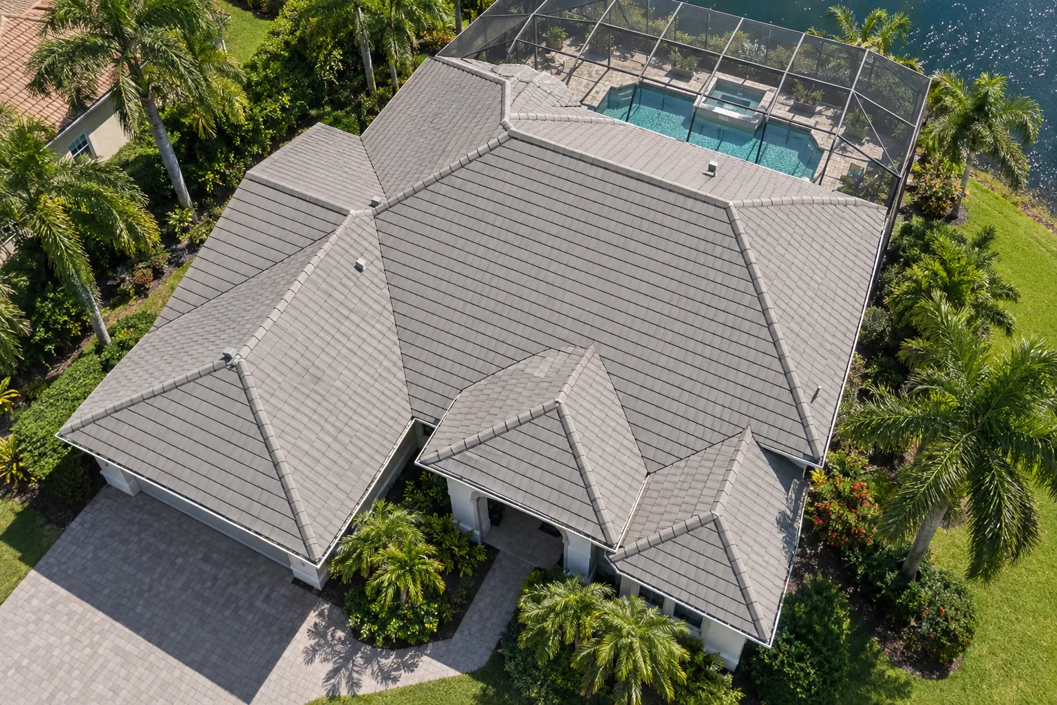 Aerial view of a Florida home with a warm gray flat concrete tile roof and complex hip-and-valley layout