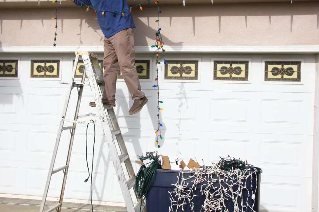 A man using a ladder to install Christmas lights on roof in Lakeland