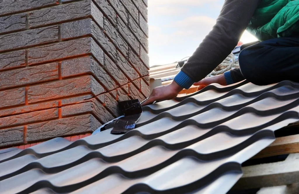 A roof professional installing flashings near chimney to avoid leaking